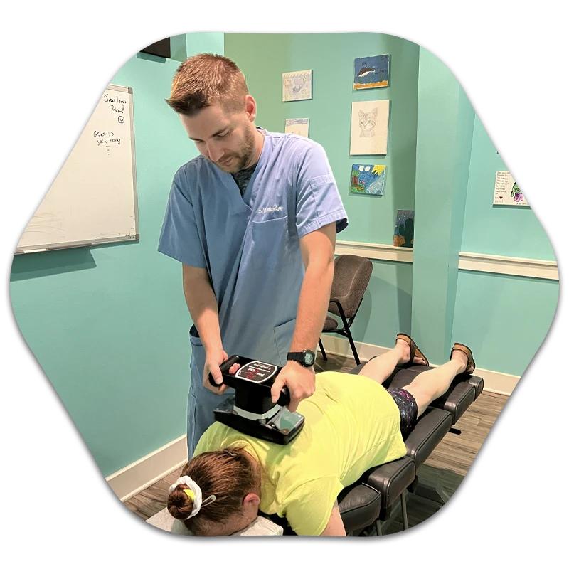 Dr. Christian Reagan applying a handheld device to another person lying face down.